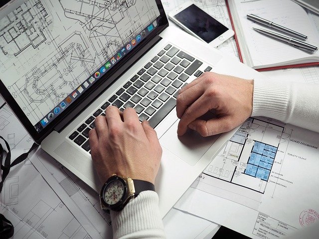 Person with building blueprints on their desk and laptop