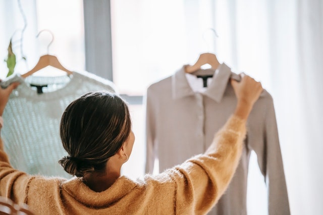 Woman choosing one of two shirts to buy