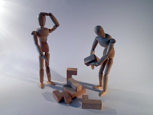 A pair of dolls confused as to how to assemble a puzzle block
