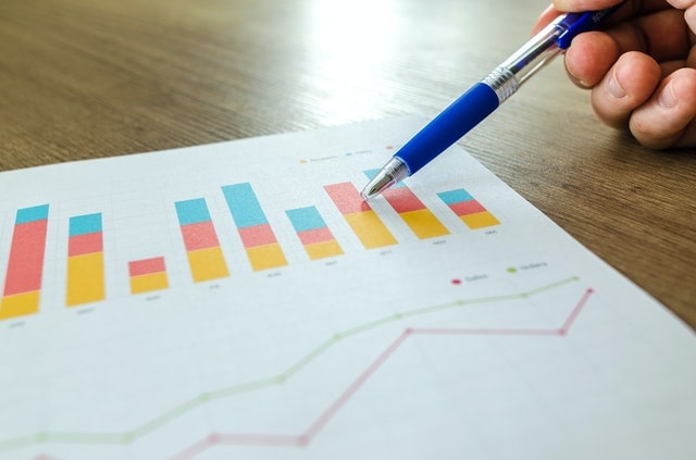 Person using a pen to point at various charts on a piece of paper